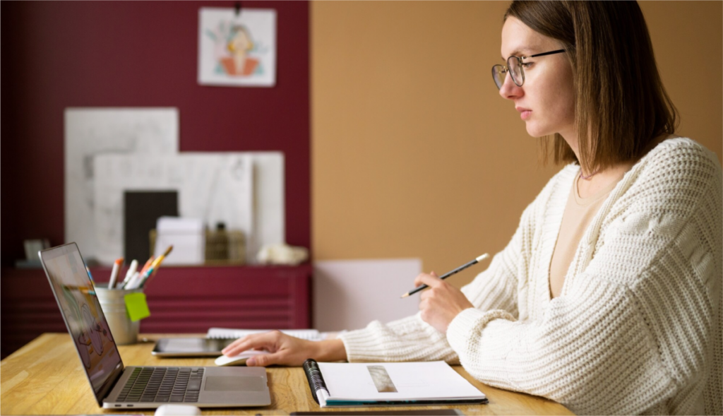 An image of a young woman reading on her laptop, illustrating the process of learning about the colon vs semicolon.